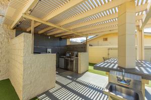 an outdoor kitchen with a wooden pergola at Kamaole Beach Royale 208 in Kihei