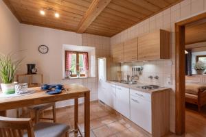 a kitchen with white cabinets and a wooden table at Ferienwohnungen „Zum Bauern“ in Oberaudorf