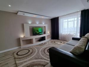a living room with a couch and a tv at Набережная Иртыша с красивым видом на реку in Ustʼ-Kamenogorsk