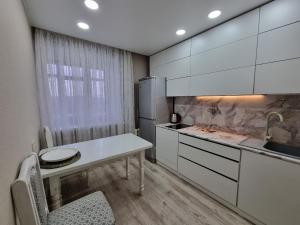a kitchen with white cabinets and a table and a sink at Набережная Иртыша с красивым видом на реку in Ustʼ-Kamenogorsk