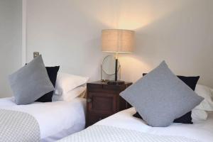a bedroom with two beds with pillows and a lamp at Luxury Pet-Friendly Retreat with Private Hot Tub in Boardmills
