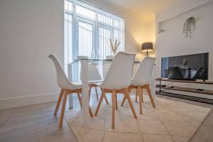 a dining room with a table and white chairs at Starfish in Porthcawl