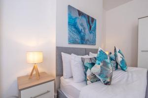 a bedroom with a white bed with pillows and a lamp at Starfish in Porthcawl