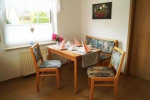 a dining room table with two chairs and a table with cards on it at Ferienhaus Kirschblüte 55182 in Stickhausen