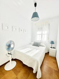 ein weißes Schlafzimmer mit einem Bett und einem Ventilator in der Unterkunft Casa 3 dormitorios La Barrosa in Chiclana de la Frontera