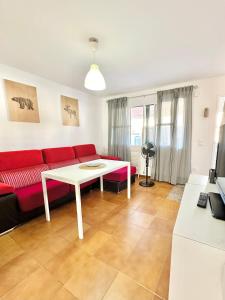 ein Wohnzimmer mit einem roten Sofa und einem Tisch in der Unterkunft Casa 3 dormitorios La Barrosa in Chiclana de la Frontera + 31 Fotos