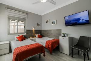 a bedroom with two beds and a flat screen tv at Urban Rooms San Roque with Solarium in Las Palmas de Gran Canaria