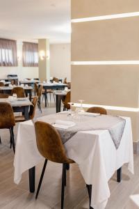 a dining room with tables and chairs with white tablecloths at Hotel BluMarine in Roseto degli Abruzzi