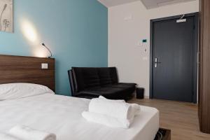 a bedroom with a bed and a black chair at Hotel BluMarine in Roseto degli Abruzzi