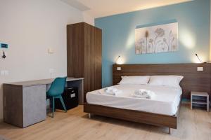 a bedroom with a bed with a desk and a chair at Hotel BluMarine in Roseto degli Abruzzi