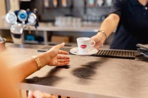 a person holding a cup of coffee on a table at Hotel BluMarine in Roseto degli Abruzzi