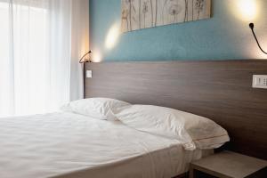 a bedroom with a white bed with a wooden headboard at Hotel BluMarine in Roseto degli Abruzzi