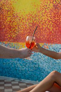 two people holding a drink in front of a pool at Hotel BluMarine in Roseto degli Abruzzi