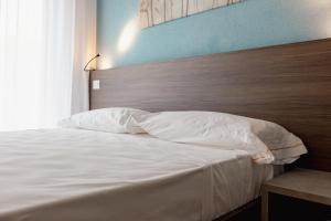 a bedroom with a white bed with a wooden headboard at Hotel BluMarine in Roseto degli Abruzzi