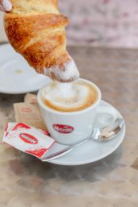 a cup of coffee with a piece of bread at Hotel BluMarine in Roseto degli Abruzzi