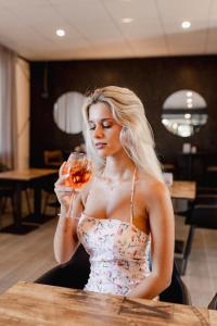 a woman sitting at a table holding a glass of wine at Hotel BluMarine in Roseto degli Abruzzi