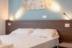 a bed with white sheets and a wooden headboard at Hotel BluMarine in Roseto degli Abruzzi