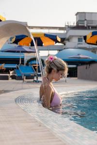 a young girl in a swimming pool with a fountain at Hotel BluMarine in Roseto degli Abruzzi