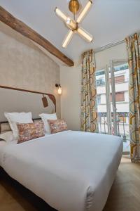 a bedroom with a large white bed with a ceiling fan at Hôtel Hiro Paris in Paris +44 photos