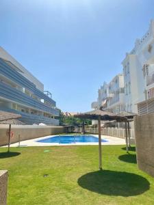 a swimming pool with an umbrella in the grass at Apartamento Atlántico in Rota