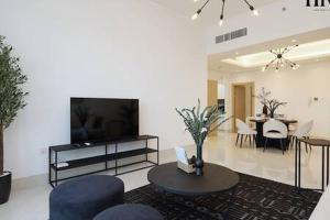 a living room with a tv and chairs and a table at Gorgeous 2 Bed Apt in Al Warqa in Dubai