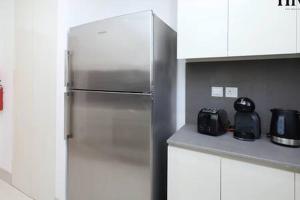 a stainless steel refrigerator in a white kitchen at Gorgeous 2 Bed Apt in Al Warqa in Dubai