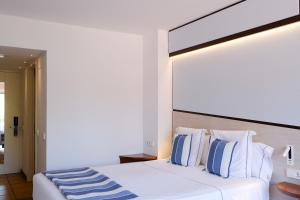 a bedroom with a white bed with blue and white pillows at Hotel Blaumar Cadaqués by Fimedhotels in Cadaqués