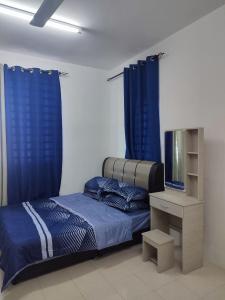 a bedroom with blue curtains and a bed and a tv at Suriati&Fhaiz Homestay in Sungai Petani