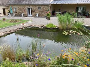 un étang en face d'une maison fleurie dans l'établissement AU COEUR DE LA BRETAGNE ,Chez Colette et Gerard, à Bazouges-la-Pérouse