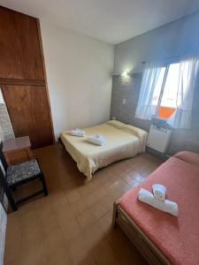 a hotel room with two beds and a chair at Hotel Atlantic in Mar de Ajó