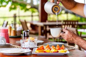 a man is pouring coffee into a cup on a table at Paka Bangalos, Pousada de Charme em Sergipe in Pacatuba