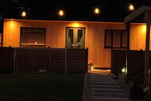 a house with lights on the side of it at night at Cozy Cabin with Modern Comforts in Wootton