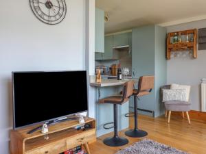 a living room with a flat screen tv and a kitchen at Pebble Beach Chalet in Seaton