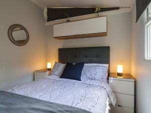 a bedroom with a bed with a blue pillow and two lights at Pebble Beach Chalet in Seaton