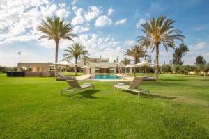a yard with two chairs and a house with palm trees at Villa des stars in Marrakesh