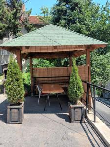 a wooden gazebo with a picnic table and two trees at Stan na dan Goca in Užice