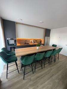 a kitchen with a large wooden table and green chairs at Apartman 100JIĆ in Nova Gradiška