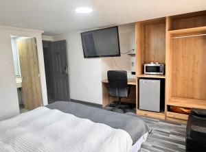 a bedroom with a bed and a desk and a tv at Hotel Fénix Real Bogotá in Bogotá