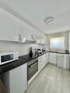 a kitchen with white cabinets and a microwave at Maison Empuriabrava proche canaux et Plage in Empuriabrava