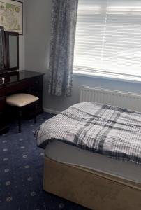 a bedroom with a bed and a desk and a window at Lilas Bangor NI in Bangor