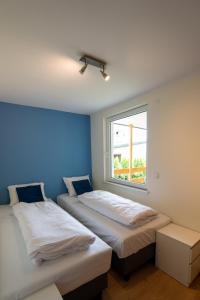 two beds in a room with a window at Domek Letniskowy 4E nad jeziorem nyskim in Skorochow