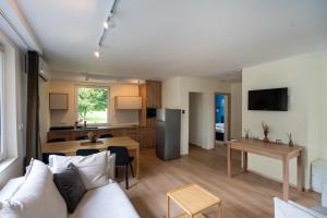 a living room with a white couch and a kitchen at Domek Letniskowy 4E nad jeziorem nyskim in Skorochow +12 photos