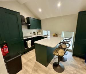 a kitchen with green cabinets and a counter with two stools at Dream Catcher One bedroom apartment in Downpatrick