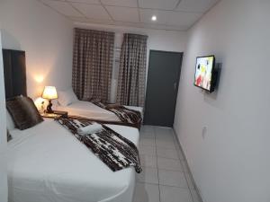 a hotel room with two beds and a tv at De Bliss Lodge in Johannesburg