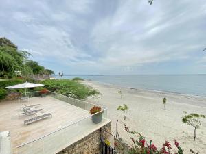 a beach with a bench and an umbrella and the ocean at Exclusiva Villa con Salida al Mar in Santa Marta