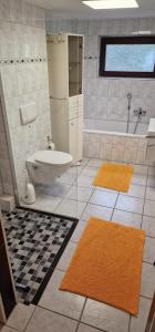 a bathroom with a tub and a toilet and two rugs at Stadtrand Haushälfte in Wilhelmshaven