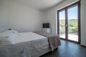 a white bedroom with a bed and a large window at Casa Vacanze Signora Cinzia in Torchiara