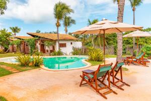 a house with a swimming pool with two chairs and an umbrella at Paka Bangalos, Pousada de Charme em Sergipe in Pacatuba