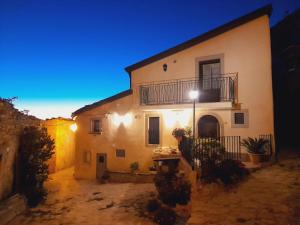 a building with a balcony and a table in front of it at La Casetta del Vento in Montalbano Elicona