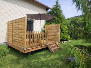 een houten dek met een parasol in het gras bij Appartement Chaleureux Gérardmer proche forêt in Gérardmer